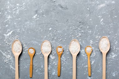 Ahşap arka planda bir sürü tahta kaşıkta tuz. Farklı tuzlu kaşıklar..