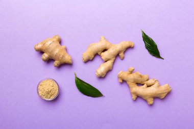Renkli arka planda yeşil yapraklı kabın içinde zencefil tozu var. Üst görünüm düzlüğü.