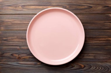 Ahşap arka planda boş pembe tabağın üst görüntüsü. Tasarımın için boş boşluk.