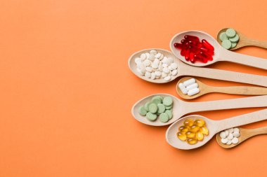 Renkli arka planda tahta kaşıkta vitamin ve mineral haplarının üst görünümü. Muhtelif ilaç haplarının en üst görüntüsü. Beslenme takviyesi sağlık ürünleri.