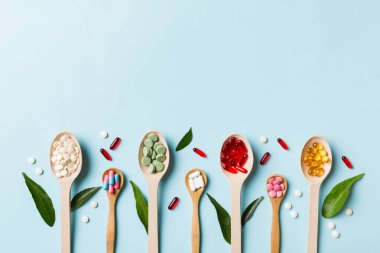 Renkli arka planda tahta kaşıkta vitamin ve mineral haplarının üst görünümü. Muhtelif ilaç haplarının en üst görüntüsü. Beslenme takviyesi sağlık ürünleri.