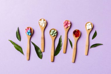 Renkli arka planda tahta kaşıkta vitamin ve mineral haplarının üst görünümü. Muhtelif ilaç haplarının en üst görüntüsü. Beslenme takviyesi sağlık ürünleri.