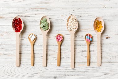 Renkli arka planda tahta kaşıkta vitamin ve mineral haplarının üst görünümü. Muhtelif ilaç haplarının en üst görüntüsü. Beslenme takviyesi sağlık ürünleri.