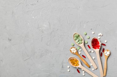 Renkli arka planda tahta kaşıkta vitamin ve mineral haplarının üst görünümü. Muhtelif ilaç haplarının en üst görüntüsü. Beslenme takviyesi sağlık ürünleri.