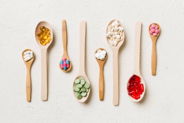 Renkli arka planda tahta kaşıkta vitamin ve mineral haplarının üst görünümü. Muhtelif ilaç haplarının en üst görüntüsü. Beslenme takviyesi sağlık ürünleri.