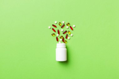 Renkli arka planda plastik şişede çok renkli haplar ve kapsüller, kopyalama alanı. Çeşitli ilaç tabletleri ve haplar, vitamin ve besin takviyeleri kavramı.