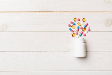 Renkli arka planda plastik şişede çok renkli haplar ve kapsüller, kopyalama alanı. Çeşitli ilaç tabletleri ve haplar, vitamin ve besin takviyeleri kavramı.