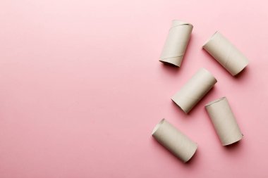 Boş tuvalet kağıdı ruloları ve renk arkaplanı üzerine metin için alanı olan düz bir kompozisyon. Kraft kağıdı veya kartondan yapılmış metal kapaklı geri dönüşümlü kağıt tüp.
