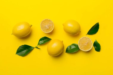 Renkli arka planda yeşil yapraklı taze limonlar, üst görünüm, metin için boşluk.