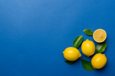 Renkli arka planda yeşil yapraklı taze limonlar, üst görünüm, metin için boşluk.