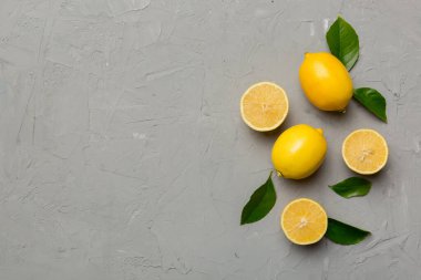 Renkli arka planda yeşil yapraklı taze limonlar, üst görünüm, metin için boşluk.