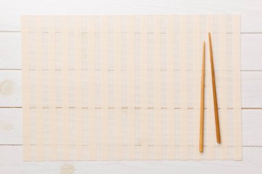 Ahşap arka planda iki çubuk ve bambu hasırı. Üst görünüm, alanı kopyala.