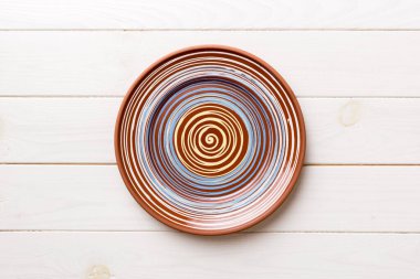 Ahşap zemindeki boş renkli tabağın üst görünümü. Tasarımın için boş boşluk.