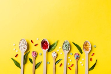 Renkli arka planda tahta kaşıkta vitamin ve mineral haplarının üst görünümü. Muhtelif ilaç haplarının en üst görüntüsü. Beslenme takviyesi sağlık ürünleri.