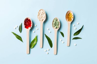 Renkli arka planda tahta kaşıkta vitamin ve mineral haplarının üst görünümü. Muhtelif ilaç haplarının en üst görüntüsü. Beslenme takviyesi sağlık ürünleri.