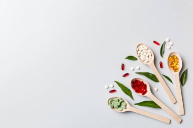 Renkli arka planda tahta kaşıkta vitamin ve mineral haplarının üst görünümü. Muhtelif ilaç haplarının en üst görüntüsü. Beslenme takviyesi sağlık ürünleri.