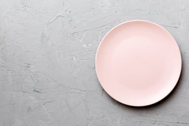 Çimento arka planındaki boş pembe tabağın üst görüntüsü. Tasarımın için boş boşluk.