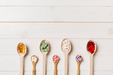 Renkli arka planda tahta kaşıkta vitamin ve mineral haplarının üst görünümü. Muhtelif ilaç haplarının en üst görüntüsü. Beslenme takviyesi sağlık ürünleri.