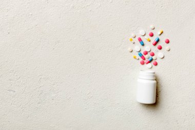 Renkli arka planda plastik şişede çok renkli haplar ve kapsüller, kopyalama alanı. Çeşitli ilaç tabletleri ve haplar, vitamin ve besin takviyeleri kavramı.