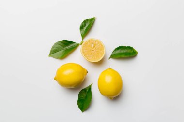 Renkli arka planda yeşil yapraklı taze limonlar, üst görünüm, metin için boşluk.