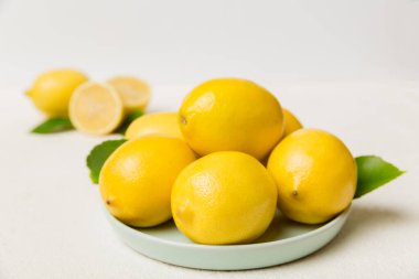 Taze kesilmiş limon ve tüm limonları renkli arka planda yuvarlak tabakta. Yemek ve içecek malzemeleri hazırlanıyor. Sağlıklı beslenme teması üst görünüm kopyalama alanı.