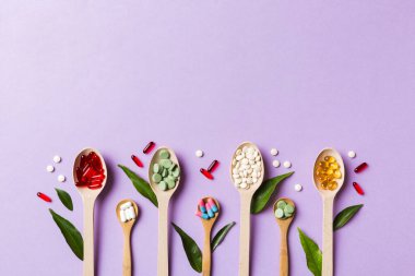 Renkli arka planda tahta kaşıkta vitamin ve mineral haplarının üst görünümü. Muhtelif ilaç haplarının en üst görüntüsü. Beslenme takviyesi sağlık ürünleri.