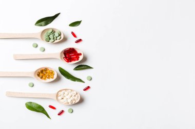 Renkli arka planda tahta kaşıkta vitamin ve mineral haplarının üst görünümü. Muhtelif ilaç haplarının en üst görüntüsü. Beslenme takviyesi sağlık ürünleri.