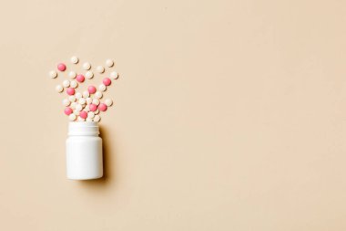 Renkli arka planda plastik şişede çok renkli haplar ve kapsüller, kopyalama alanı. Çeşitli ilaç tabletleri ve haplar, vitamin ve besin takviyeleri kavramı.