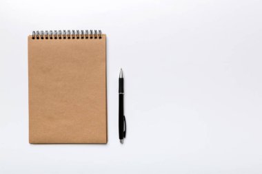 Renkli bir arka planda okul kahverengi defteri, bir masadaki spiral el işi not defteri..