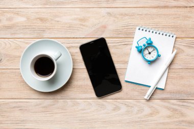 Modern ofis masası, defter, akıllı telefon ve kahve ile birlikte diğer malzemeler. Tasarım için boş defter sayfası. Üst manzara, düz uzanma.