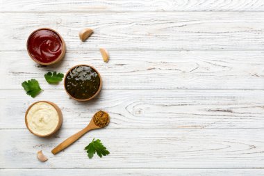 Masa arkaplanındaki kaşıklarda farklı soslar, düz üst görünüm.