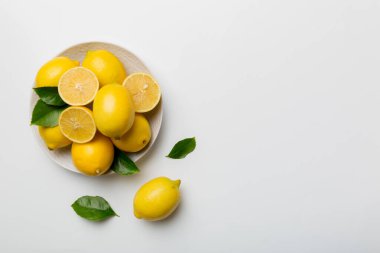 Taze kesilmiş limon ve tüm limonları renkli arka planda yuvarlak tabakta. Yemek ve içecek malzemeleri hazırlanıyor. Sağlıklı beslenme teması üst görünüm kopyalama alanı.