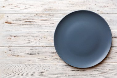 Ahşap zemindeki boş gri tabağın üst görüntüsü. Tasarımın için boş boşluk.