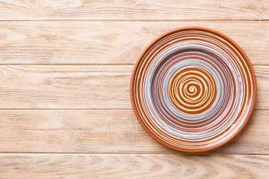 Ahşap zemindeki boş renkli tabağın üst görünümü. Tasarımın için boş boşluk.