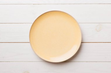 Ahşap arka planda boş turuncu tabağın üst görüntüsü. Tasarımın için boş boşluk.