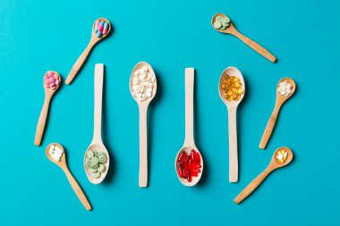 Renkli arka planda tahta kaşıkta vitamin ve mineral haplarının üst görünümü. Muhtelif ilaç haplarının en üst görüntüsü. Beslenme takviyesi sağlık ürünleri.