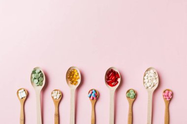Renkli arka planda tahta kaşıkta vitamin ve mineral haplarının üst görünümü. Muhtelif ilaç haplarının en üst görüntüsü. Beslenme takviyesi sağlık ürünleri.