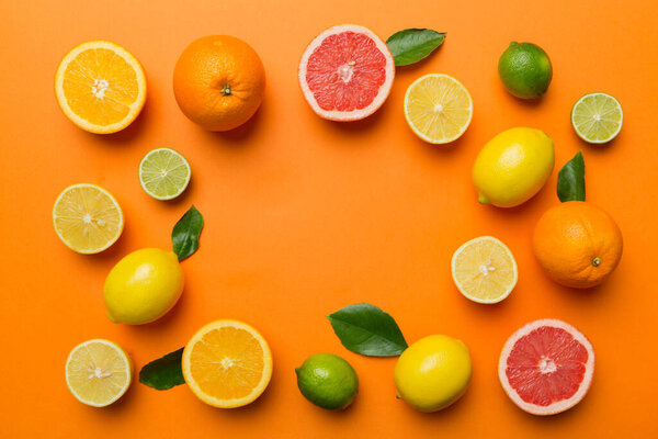 Flat lay of citrus fruits like lime, orange and lemon with lemon tree leaves on light colored background making a frame. Space for text healthy concept.