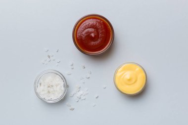 Renkli arkaplanda bir kase tuz, ketçap ve peynir sosu, fotokopi alanı ile üst manzara.