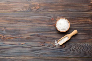 Ahşap bir arka planda ahşap bir kase tuz kristali. Kırsal kaselerdeki tuz, fotokopi alanı olan üst görünüm.