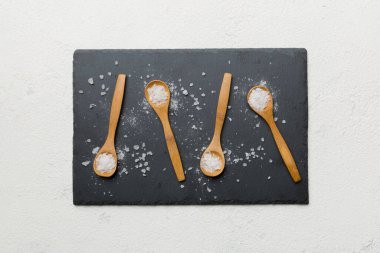 Ahşap arka planda bir sürü tahta kaşıkta tuz. Farklı tuzlu kaşıklar..