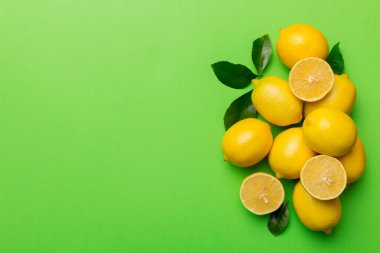 Renkli arka planda yeşil yapraklı taze limonlar, üst görünüm, metin için boşluk.