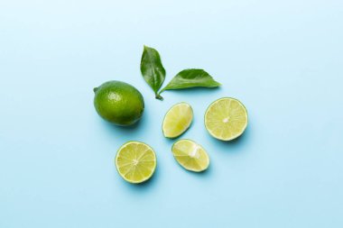 Yeşil yapraklı kireç meyveleri ve beyaz arka planda yarım dilim kesilmiş. Üst Manzara. Kopyalama alanı olan düz.