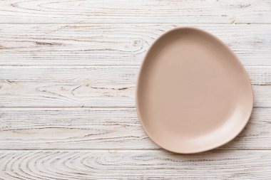 Ahşap arka planda boş pembe tabağın üst görüntüsü. Tasarımın için boş boşluk.