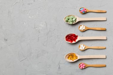 Renkli arka planda tahta kaşıkta vitamin ve mineral haplarının üst görünümü. Muhtelif ilaç haplarının en üst görüntüsü. Beslenme takviyesi sağlık ürünleri.