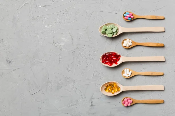 Renkli arka planda tahta kaşıkta vitamin ve mineral haplarının üst görünümü. Muhtelif ilaç haplarının en üst görüntüsü. Beslenme takviyesi sağlık ürünleri.