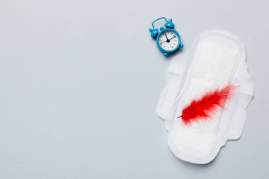 Alarm saatini hijyenik kadın tamponları ve regl pedleri ile çalıyor. Tıbbi konsept kadın kritik günler ve regl dönemi. Kadın günlük hijyen. Boşluğu kopyala.