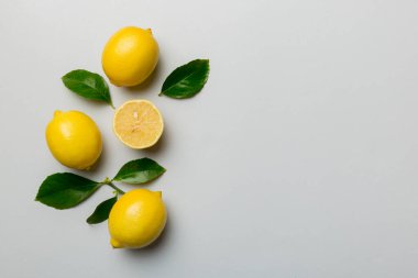 Renkli arka planda yeşil yapraklı taze limonlar, üst görünüm, metin için boşluk.