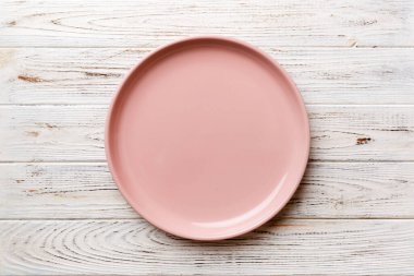 Ahşap arka planda boş pembe tabağın üst görüntüsü. Tasarımın için boş boşluk.