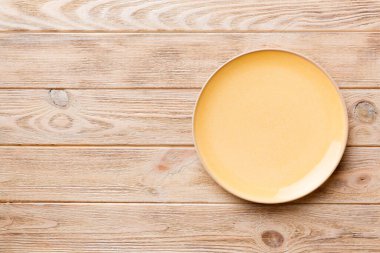 Ahşap arka planda boş turuncu tabağın üst görüntüsü. Tasarımın için boş boşluk.